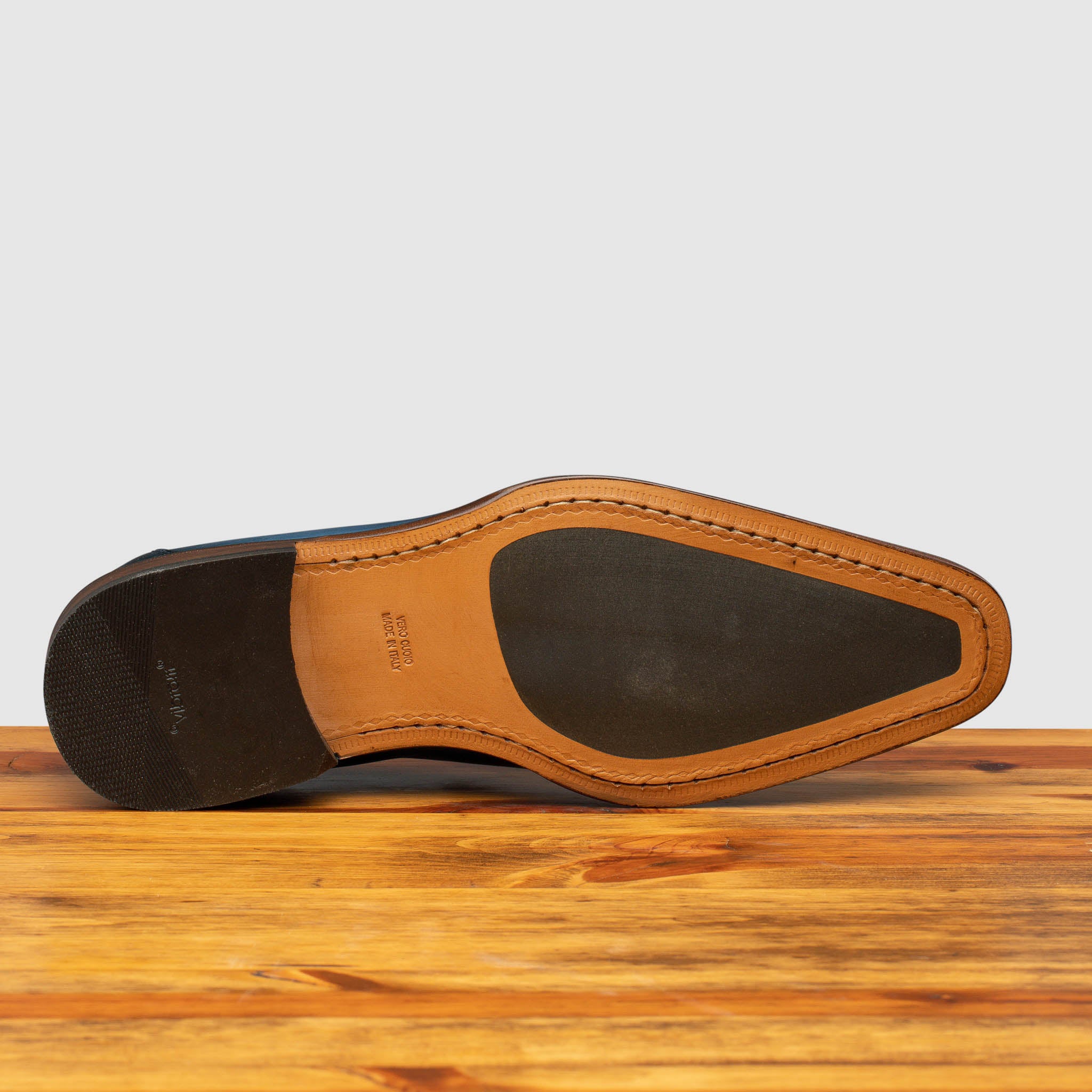 Injected Rubber Sole and Heel of Z993 Calzoleria Toscana Ocean Blue David Tassel Slip-On on top of a wooden table